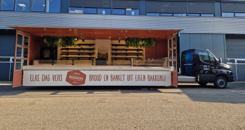 Zijaanzicht van een verkoopwagen oplegger voor brood en banket met geopende luifel
