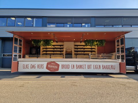 Zijaanzicht van een verkoopwagen oplegger voor brood en banket met geopende luifel