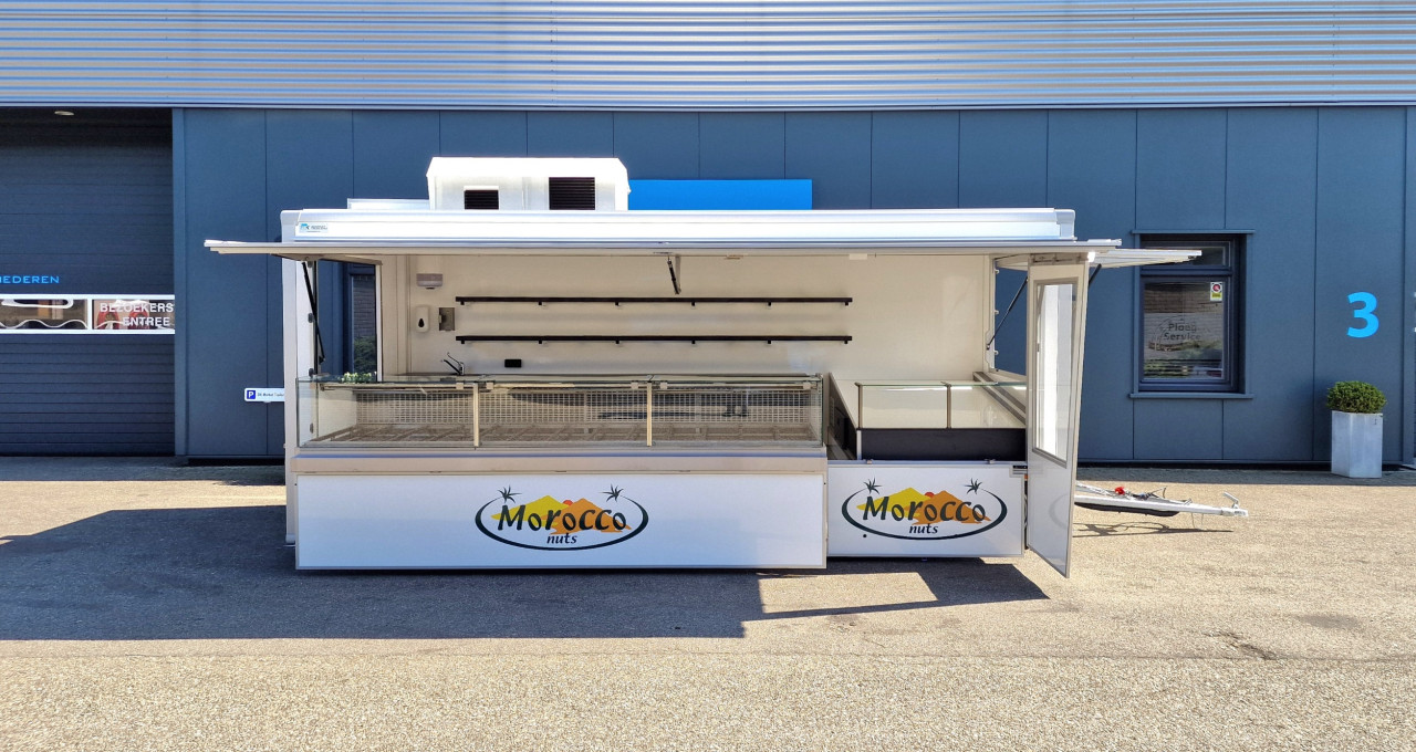 Zijaanzicht van een aanhangwagen voor noten met geopende luifel en zijbord