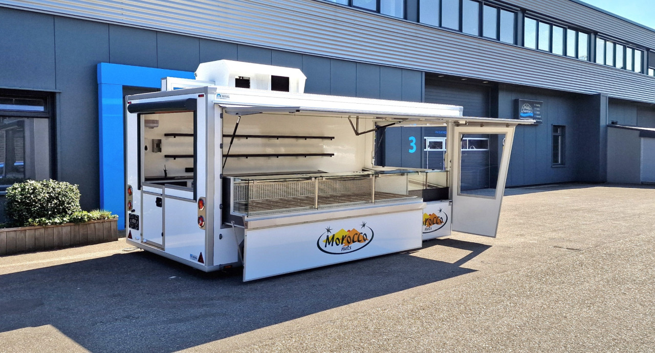 Zijaanzicht van een aanhangwagen voor noten met geopende luifel en zijbord